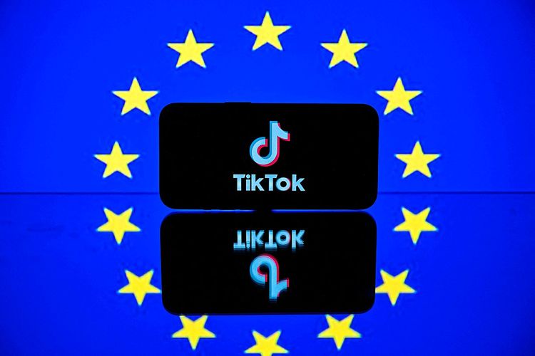 Das Tiktok-Logo auf einem Smartphone vor der EU-Flagge