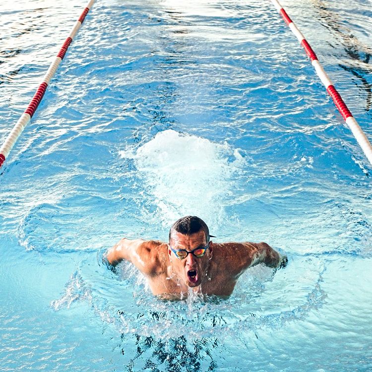 Mann schwimmt mit Delfintechnik in einem Pool