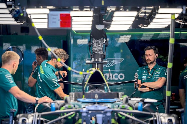 Mechaniker des Aston-Martin-Teams arbeiten in der Garage am Hungaroring-Rennstreckenkomplex in Mogyoród, nahe Budapest, Ungarn. Im Vordergrund sind Teile eines Rennwagens sichtbar, beleuchtet von mehreren Lampen.