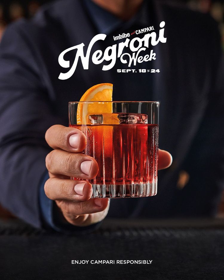 Eine Hand mit einem Glas Negroni.