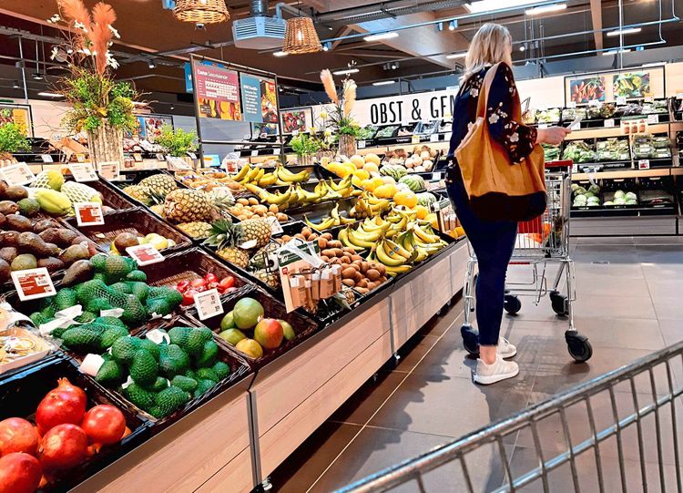 Frau steht im Supermarkt vor einer Obsttheke