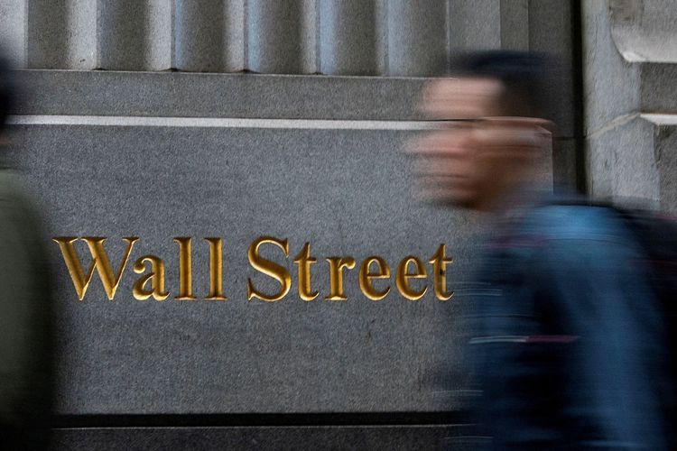 Ein Mann geht vor einem Schild mit der Aufschrift Wall Street.
