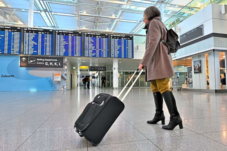 Reisende vor Anzeigetafel am Flughafen München