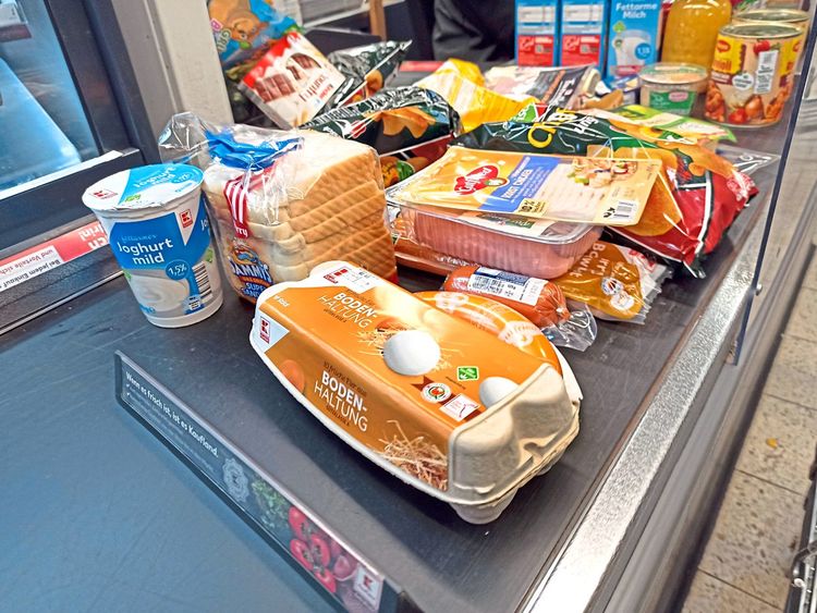 Eine Supermarktkassa mit etlichen Produkten auf dem Fließband.