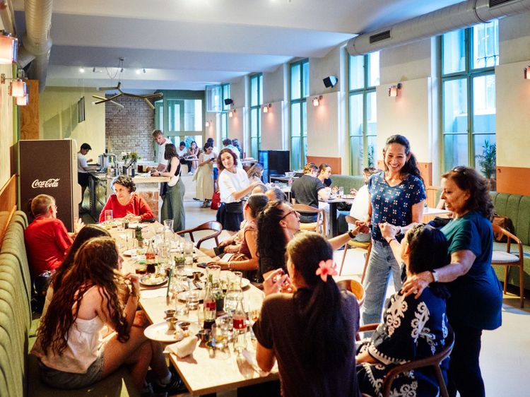 Viele Menschen sitzen am Tisch im Souterrain gelegenen Restaurant.