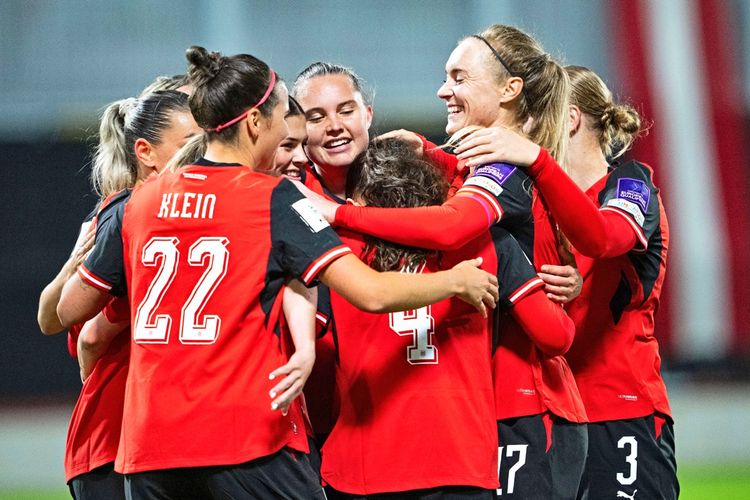 Mehrere Spielerinnen der österreichischen Fußballnationalmannschaft umarmen sich jubelnd nach einem Tor während des Play-off-Rückspiels der WM-Qualifikation gegen Kosovo in Wien. Sie tragen rote Trikots mit schwarzen Ärmeln.