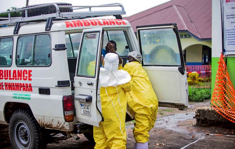 Kongolesische Gesundheitsarbeiter in gelber Schutzkleidung bringen einen Patienten in einem weißen Rettungswagen mit der Aufschrift 