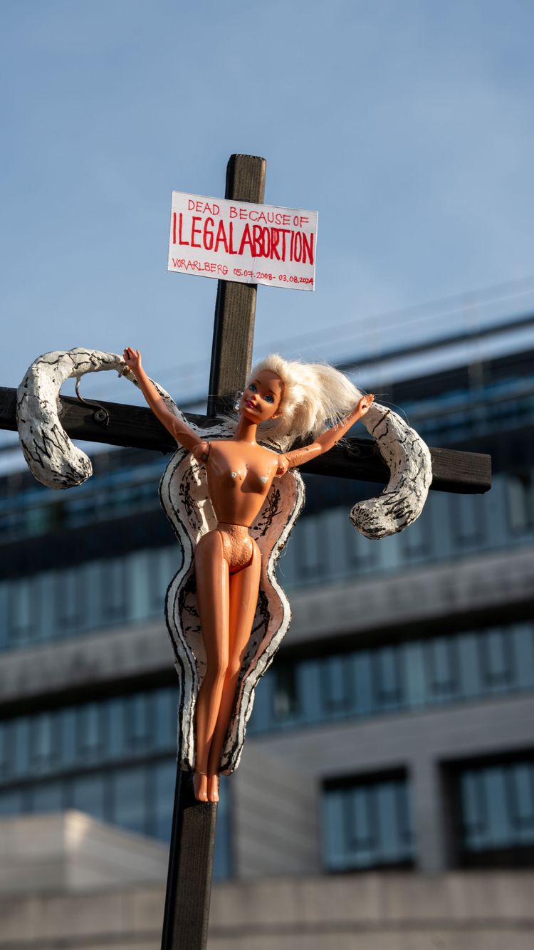 Ein Kreuz mit Barbie-Puppe und Aufschrift beim Protest für sichere Abtreibungen am 28. September 2023 in Bregenz