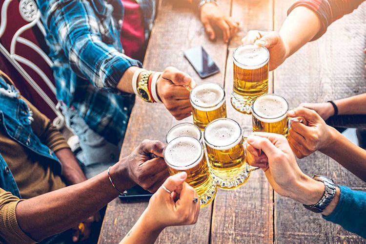 Gasthaus-Szene: Mehrere Menschen stoßen mit Biergläsern an, nur die Hände sind zu sehen