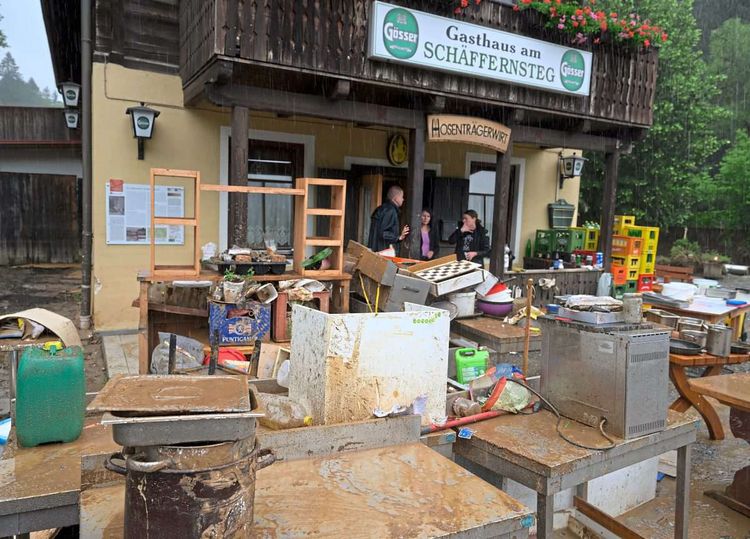 Vor einem Gasthaus stehen zahlreiche Kücheneinrichtungsgegenstände, die vom Hochwasser zerstört wurden. 
