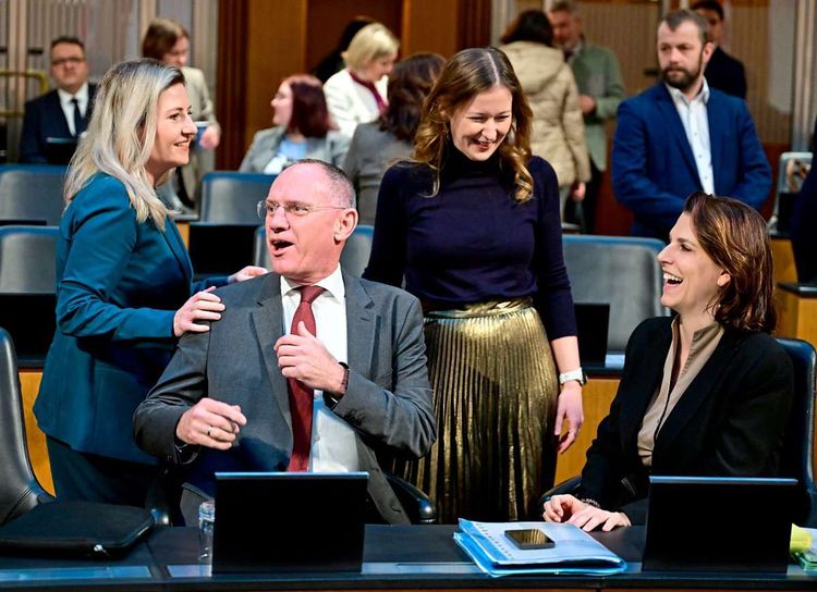 Susanne Raab, Gerhard Karner, Claudia Plakolm und Karoline Edtstadler stehen bzw. sitzen nebeneinander im Nationalratsplenum.