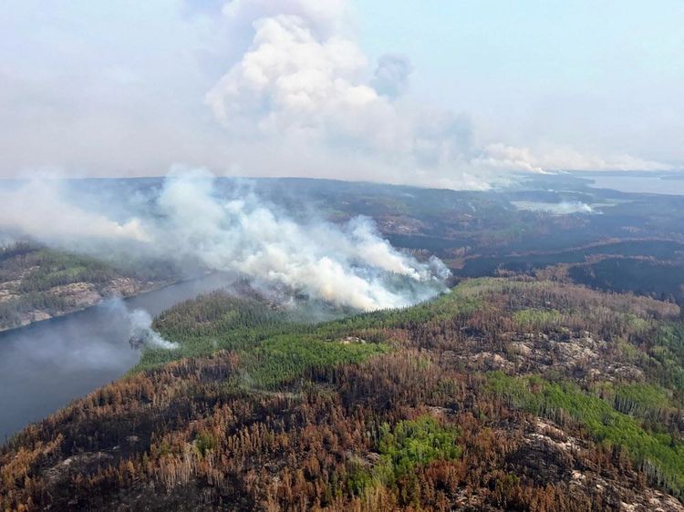 Luftaufnahme, in Kanada tobt ein Waldbrand, Rauch steigt auf. 