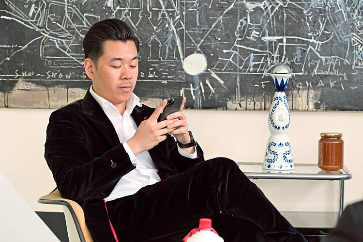 Martin Ho sitzt auf einem Sessel und schaut in sein Smartphone.