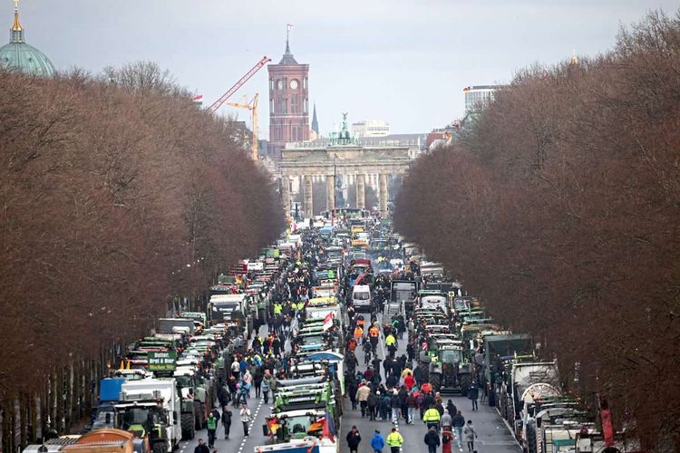 Dutzende Traktoren auf der Straße, die zum Brandenburger Tor im Hintergrund führt.