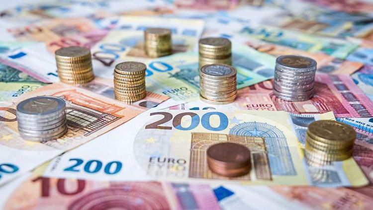 Euro-Scheine und Münzen liegen durcheinander auf einem Tisch.
