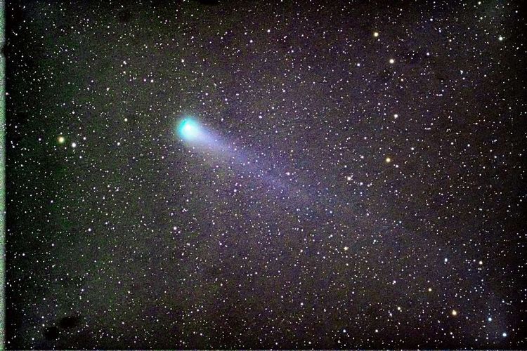Der Komet als heller, verschwommener Punkt mit Schweif vor dem Sternenhimmel.