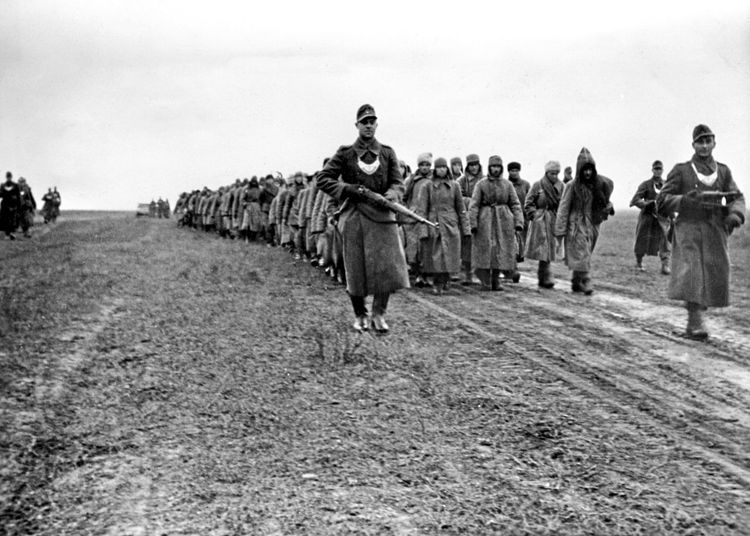Feldgendarmen der deutschen Wehrmacht bewachen auf einem Marsch sowjetische Kriegsgefangene.