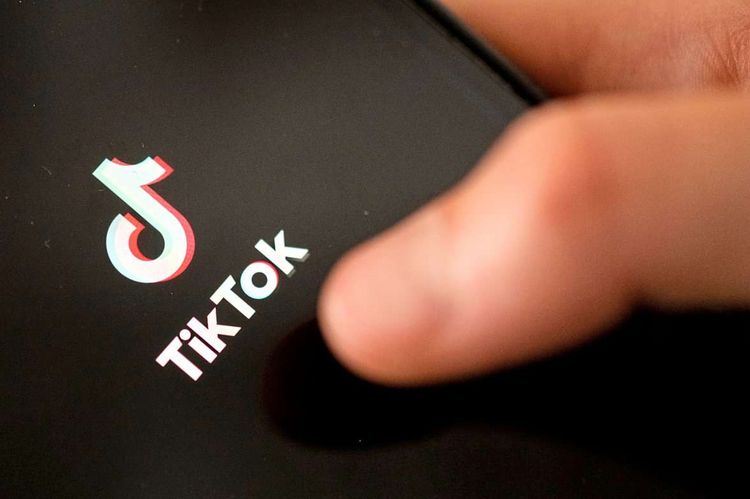 Ein Teenager tippt auf das TikTok-Logo auf einem Smartphone