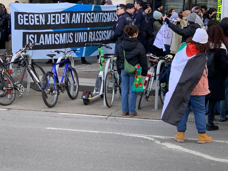 Demonstrierende mit Transparenten und Palästina-Flagge