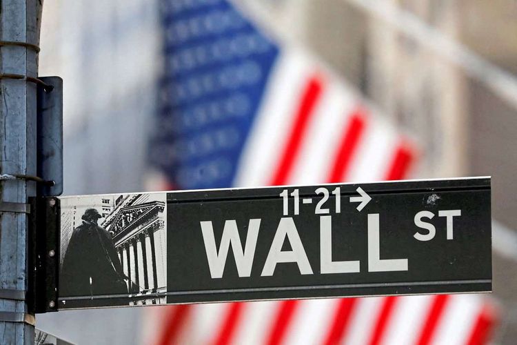 Das Straßenschild der Wall Street, dahinter ist eine US-Flagge zu sehen.