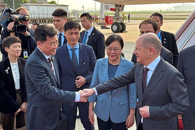 Deutschlands Kanzler Olaf Scholz schüttelt bei seiner Ankunft am Flughafen in Chongqing dem chinesischen Botschafter in Deutschland Wu Ken neben dem Vizebürgermeister von Chongqing, Zhang Guozhi, die Hand.