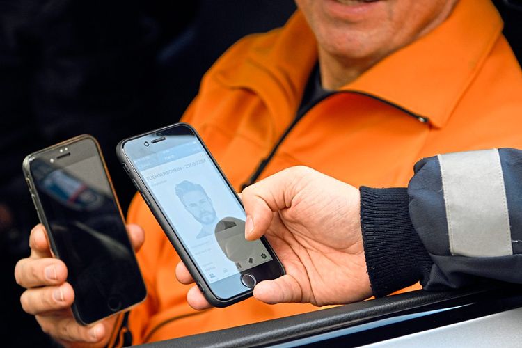 Polizist kontrolliert digitalen Führerschein eines Autofahrers.
