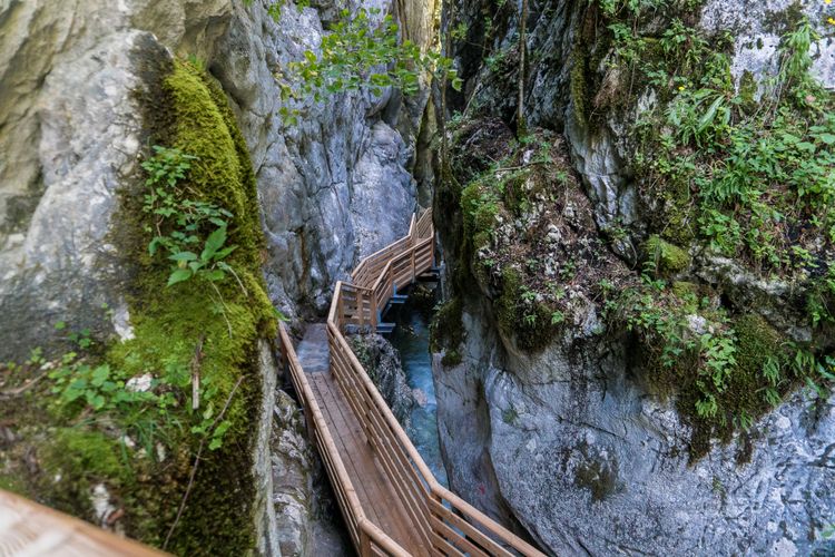 Ein Holzsteg zwischen Felswänden, darunter ein Fließgewässer
