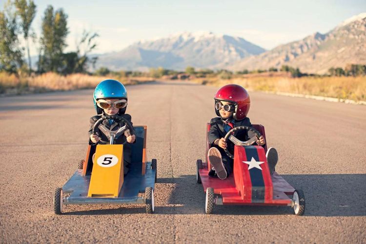 Zwei Kinder in kleinen Go-Karts nebeneinander kurz vor einem Rennen