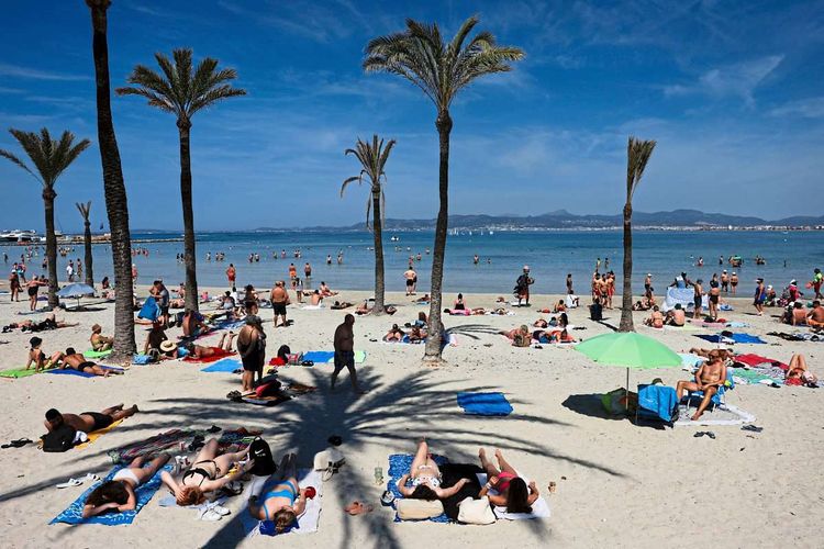 Touristen liegen am Strand in Palma de Mallorca.