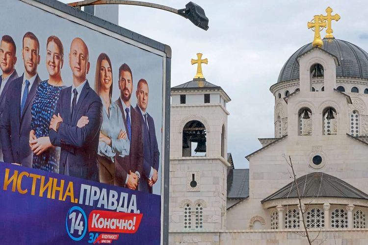 Ein Wahlplakat einer pro-serbischen und pro-russischen Koalition neben einer serbisch-orthodoxen Kirche in Podgorica