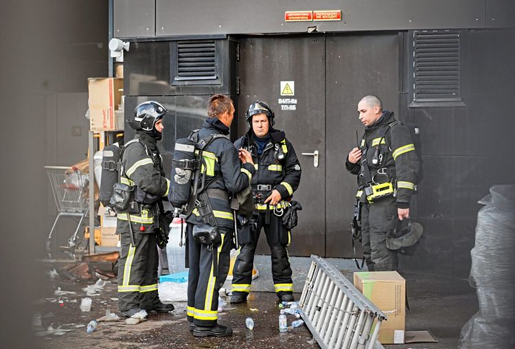 Vier Feuerwehrleute sind vor dem Einkaufszentrum zu sehen.