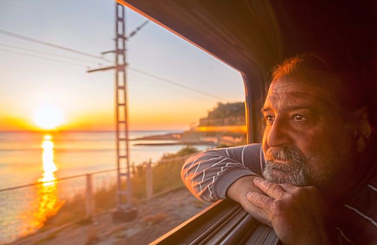 Ein Mann sitzt im Zug und schaut aus dem Fenster.