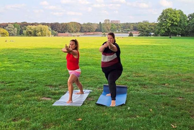 Heide Fuhljahn mit Yogalehrerin im Park bei Yogapose