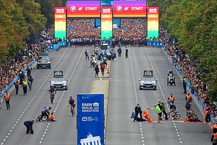 Start des Berlin-Marathons, Protestanten schütten orange Farbe auf den Asphalt