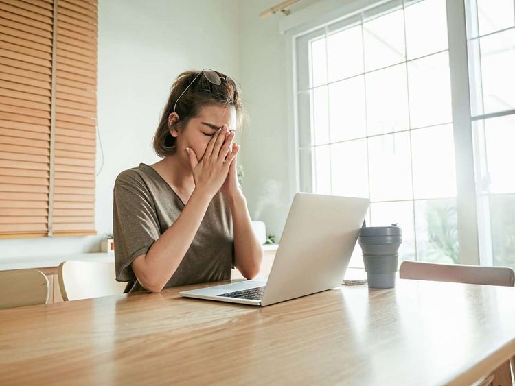 Bild zeigt eine Frau, die verzweifelt vor einem Laptop am Schreibtisch sitzt.