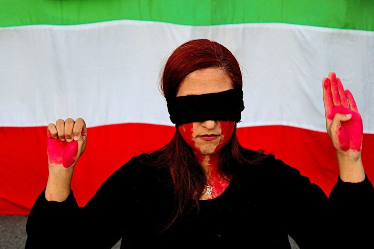 Demonstrantin in Barcelona vor iranischer Fahne.