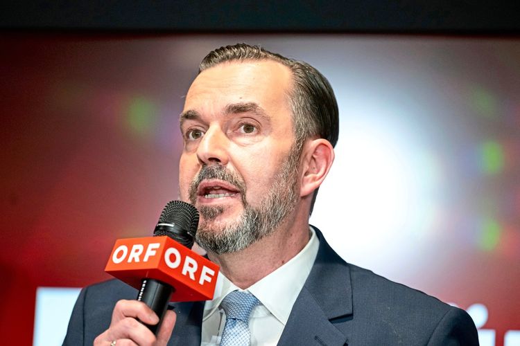 Ein Mann in einem Anzug hält ein Mikrofon mit rotem 