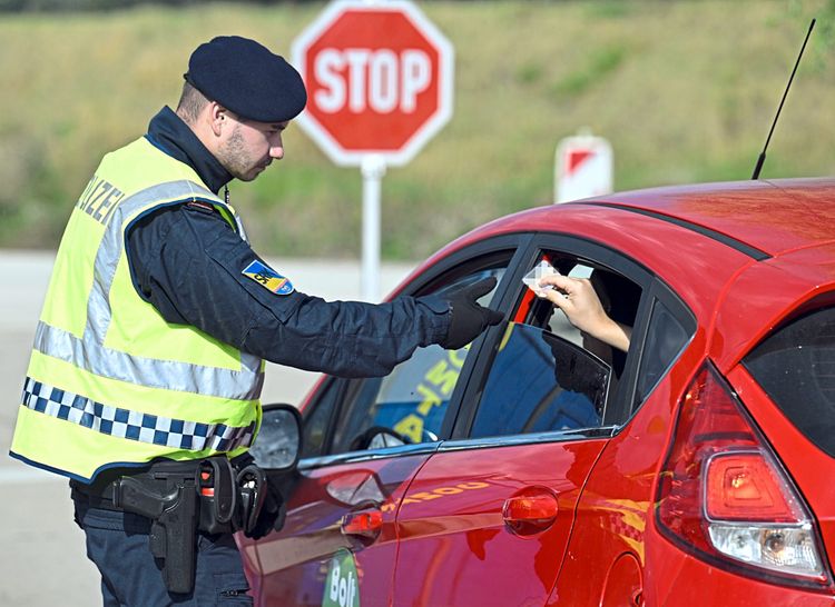 Ein Polizist verlangt den Ausweis eines Autofahrers.