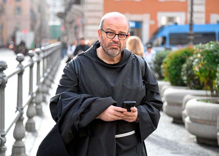 Mann in Mönchskutte mit Handy.
