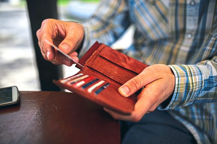 Mann steckt Kreditkarten in Geldbörse