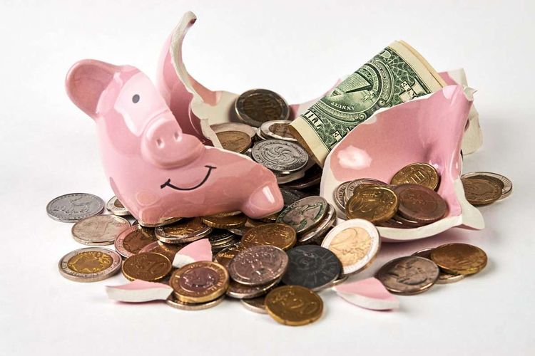 Zerbrochenes Sparschwein mit Münzen und einem Geldschein