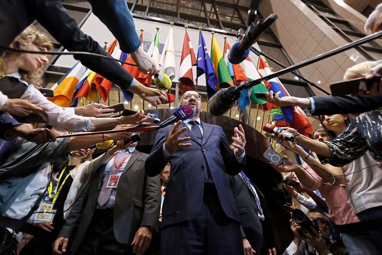 EU-Ratspräsident Charles Michel in Brüssel, umringt von Medienvertretern mit Mikrofonen.