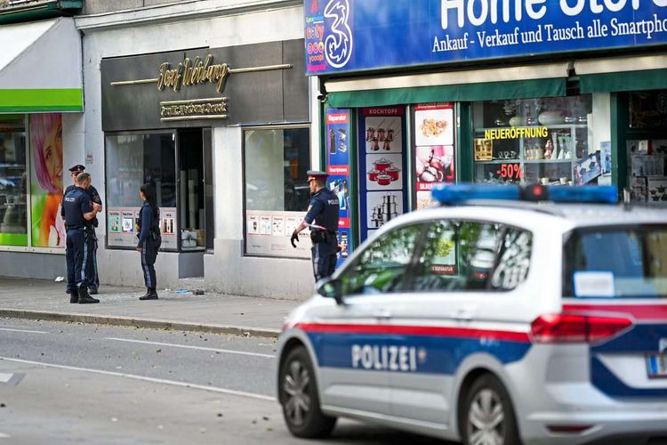 Uniformierte Polizisten und ein Streifenwagen stehen nach einem Mord am 7. Mai 2023 auf der Simmeringer Hauptstraße.