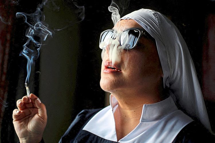 Nonne mit Sonnenbrille raucht einen Joint