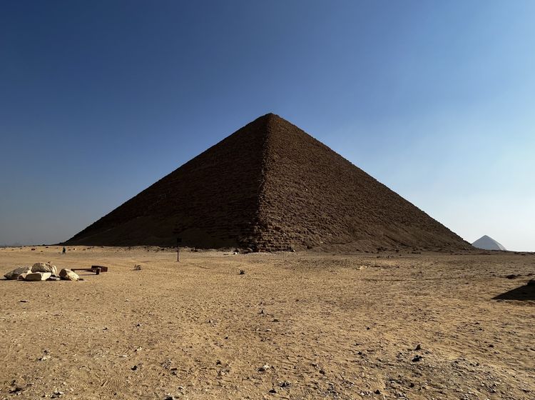 In der Wüste erhebt sich eine Pyramide vor blauem Himmel.
