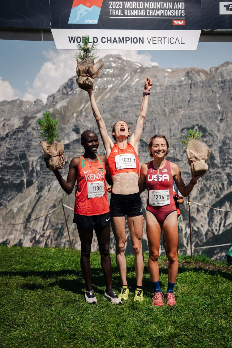 Das Podium nach einem Berglauf: Drei jubelnde Frauen im Laufdress.